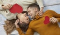 Happy couple in love lying on floor, holding red Valentines, looking at each other and smiling Royalty Free Stock Photo