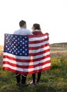 happy couple in love, a man and a woman, hold an American flag behind their backs, illuminated by sunlight