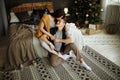 Happy couple in love in the morning on the bed near the Christmas tree, hug and kiss, Christmas morning. nearby, on the floor are Royalty Free Stock Photo