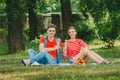 Happy couple in love resting in the park on the meadow. A couple of young people are sitting on a bed in a park in the summer and Royalty Free Stock Photo