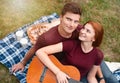 Happy couple in love on a romantic date at the park on a picnic. Playing on a guitar and having fun outdoors Royalty Free Stock Photo