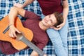 Happy couple in love on a romantic date at the park on a picnic. Playing on a guitar and having fun outdoors Royalty Free Stock Photo