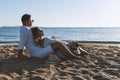 Happy couple in love, is seating on the beach during sunset or sunrise. Summer vacations Royalty Free Stock Photo