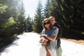 Happy couple in love spending time together in the mountains on a walk, standing in the snow in the woods, hugging and looking at Royalty Free Stock Photo