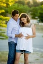 Happy couple in love together in park landscape on sunset with woman pregnant belly and man Royalty Free Stock Photo