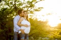 Happy couple in love together in park landscape on sunset with woman pregnant belly and man Royalty Free Stock Photo