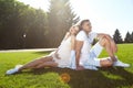 Happy couple in love waiting for child pregnancy hug in the summer park green trees sitting on the grass rest nature husband wife