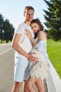 Happy couple in love waiting for child pregnancy hug walk in the summer park green trees nature husband and wife baby boy young