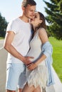 Happy couple in love waiting for child pregnancy hug walk in the summer park green trees nature husband and wife baby boy young