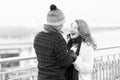 Couple loves walking around river. woman and man laughing on street. Man in woolen hat makes funny woman in knitted scurf