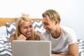 Happy couple lying on bed while using laptop computer - Happy people having funny movie bed time Royalty Free Stock Photo