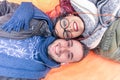 Happy couple lying down holding heads together looking up at the camera as posing for a selfie photo - Lovers hearing music Royalty Free Stock Photo