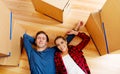 Happy couple lying on the floor in new home with cordboard boxes around Royalty Free Stock Photo