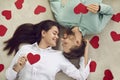 Happy couple lying on floor among red Valentine cards, looking at each other and smiling Royalty Free Stock Photo