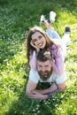 Happy couple lying on green grass meadow. Bearded man and brunette girl on picnic, spring time concept. Smiling man