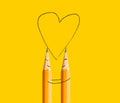 A happy couple made of pencils with painted smiley and hugging drawing a heart shape