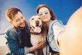 Happy couple making selfie photo with new pet dog retriever Labrador outdoors. Lifestyle summer walk concept Royalty Free Stock Photo