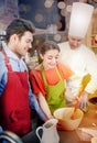Happy couple and male chef cook cooking in kitchen Royalty Free Stock Photo