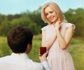 Happy couple, man kneeling down and proposing ring to his woman outdoors on the grass, wedding concept Royalty Free Stock Photo