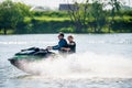 Happy couple of man and woman drives jet ski at sunset by river bank at countryside. Extreme sports and active family summer Royalty Free Stock Photo