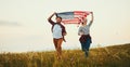 Happy couple man and woman with flag of united states enjoying the sunset on nature Royalty Free Stock Photo