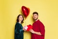 Happy couple, man and woman holding balloons shaped hearts and gift box. Valentine's day celebration. Concept of Royalty Free Stock Photo