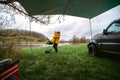 Happy couple, man and woman hugging in wilderness. Yellow raincoats from bad weather. A gloomy spring day. Camping by SUV car. Royalty Free Stock Photo