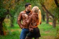 The happy couple, man and woman posing outdoor in the green autumn park in the red bomber leather coats