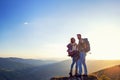 Happy couple man and woman tourist at top of mountain at sunset outdoors during a hike in summer Royalty Free Stock Photo