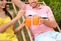 Couple with mason jars of refreshing drink resting in deck chairs outdoors, closeup