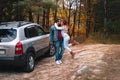 Happy couple, man and woman. Family and travel concept. Universal SUV car on a dirt road, autumn forest in the background Royalty Free Stock Photo