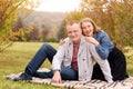 Happy couple, man and woman in autumn park sitting on a plaid. Beautiful smiling couple enjoying picnic day in the park Royalty Free Stock Photo