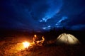 Couple man and woman tourists having a rest at night camping in the mountains under cloudy sky Royalty Free Stock Photo