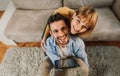 Happy couple of millennials using digital tablet at home. Boyfriend and girlfriend sitting on the sofa