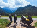 Happy couple of motorcyclists adventure bikers. Green meadow in Zgornje Jezersko, to Kamnik-Savinja Alps on a sunny summer day in