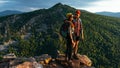 A happy couple in the mountains admires the beautiful views. Travelers enjoy climbing the mountain at sunset Royalty Free Stock Photo