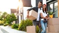 Happy couple with moving boxes and household stuff near their new house Royalty Free Stock Photo