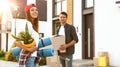 Happy couple with moving boxes and household stuff near their new house Royalty Free Stock Photo