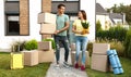 Happy couple with moving boxes and household stuff near their new house Royalty Free Stock Photo