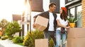 Happy couple with moving boxes and household stuff near their new house Royalty Free Stock Photo