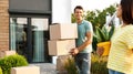 Happy couple with moving boxes and household stuff near their new house Royalty Free Stock Photo