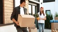 Happy couple with moving boxes and household stuff near their new house Royalty Free Stock Photo