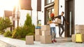 Happy couple with moving boxes and household stuff near their house on sunny day Royalty Free Stock Photo