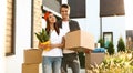 Happy couple with moving boxes and household stuff near their new house Royalty Free Stock Photo