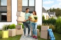 Happy couple with moving boxes and household stuff near their new house Royalty Free Stock Photo