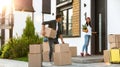 Happy couple with moving boxes and household stuff near their house on sunny day Royalty Free Stock Photo