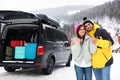 Happy couple near car with open trunk on road. Winter vacation Royalty Free Stock Photo