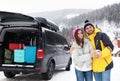 Happy couple near car with open trunk on road. Winter vacation Royalty Free Stock Photo