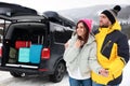 Couple near car with open trunk on snowy road. Winter vacation Royalty Free Stock Photo