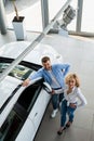 Happy couple near their new car in dealership. Royalty Free Stock Photo